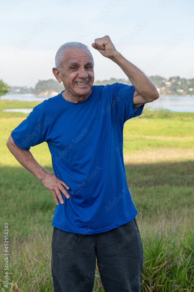 Fototapeta premium portrait of an active and happy senior man excited and celebrating with hand up outside on a sunny day