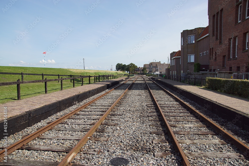 Railroad tracks of the steam tram in the Dutch city of Medemblik with next to it the dike along the IJsselmeer. Summer, August, Netherlands. 