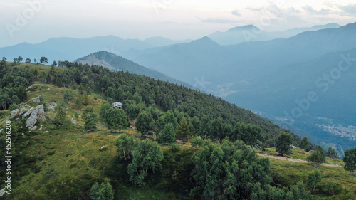 Aerial view of green fields and forest in the mountains. Italian Alps.