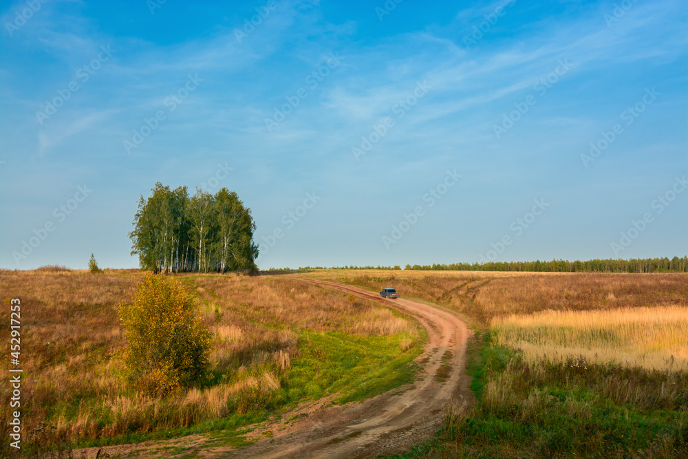 country road with a car in the autumn evening