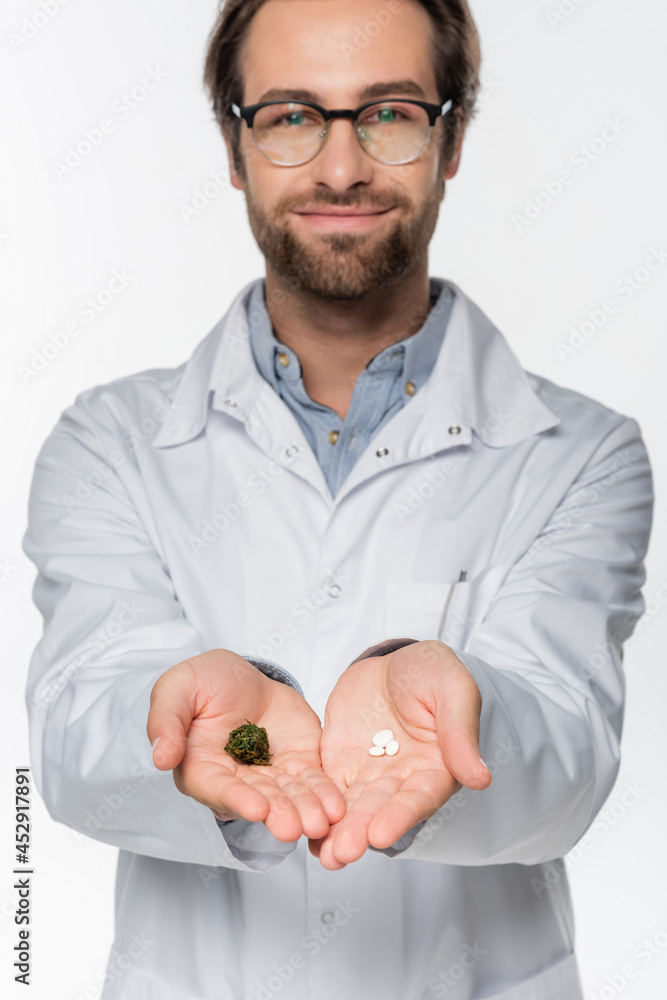 smiling doctor with dry medical cannabis and pills in hands isolated on white smiling doctor with dry medical cannabis and pills in hands isolated on white