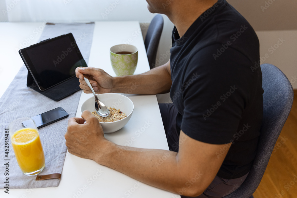Crop man eating muesli for breakfast at home Crop man eating muesli for breakfast at home