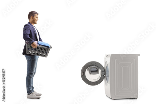 Full length profile shot of a man with a laundry basket standing in front of a washing machine