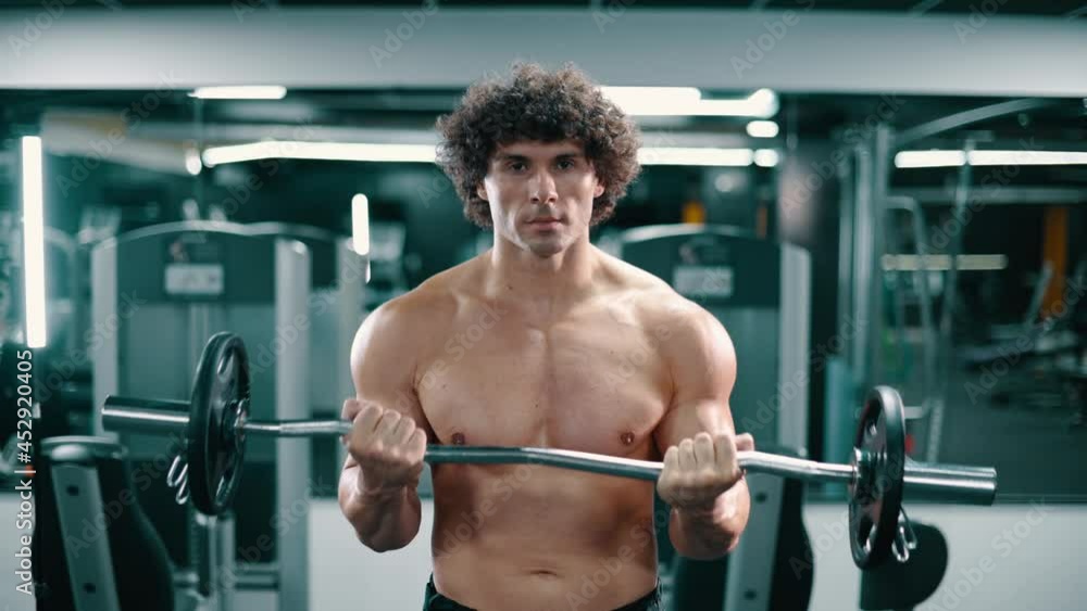 Athletic man doing weight lifting. Lifting bar for biceps training. Camera moves away from athlete. Athletic man doing weight lifting. Lifting bar for biceps training. Camera moves away from athlete.