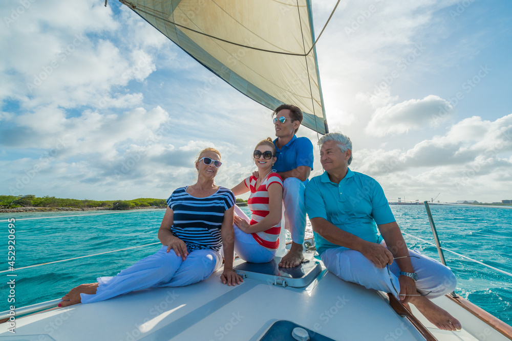 Obraz premium Senior and young couples, family, enjoying sailing trip on a luxury summer holiday vacation, sunset and ocean in background, love and romance on a beautiful yacht