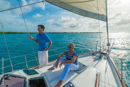 Smiling people, mother and son enjoying sailing trip on a luxury summer holiday vacation, sunset and ocean in background