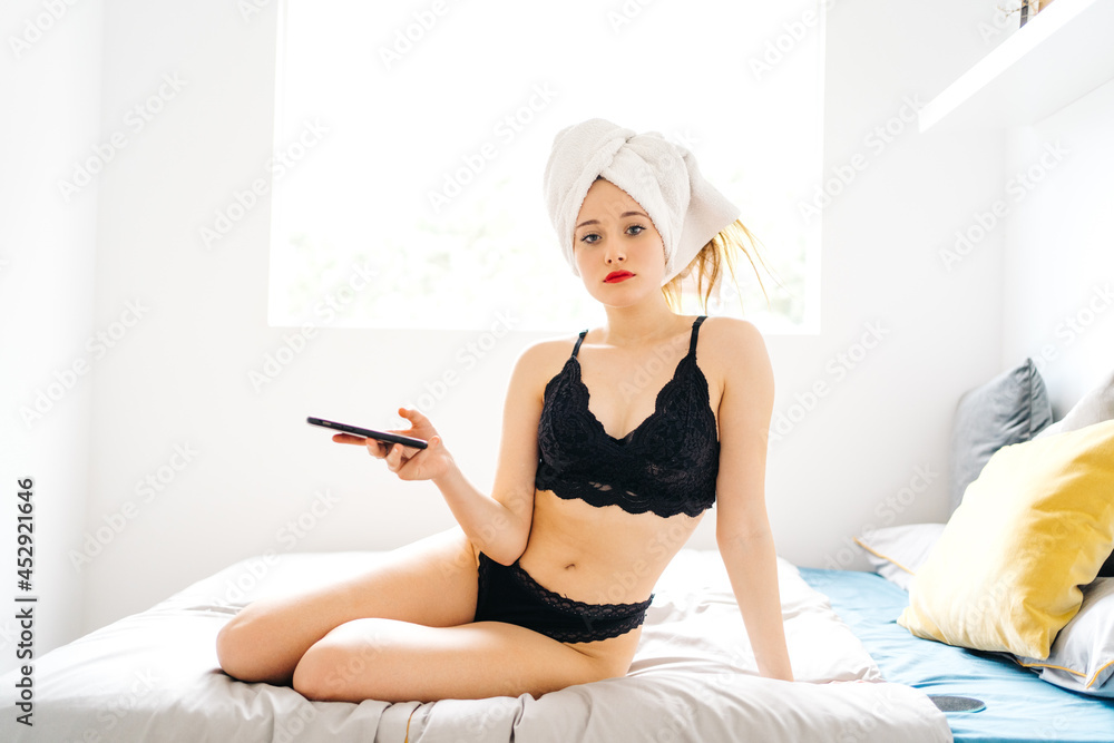 Content woman browsing smartphone on bed in morning Content woman browsing smartphone on bed in morning