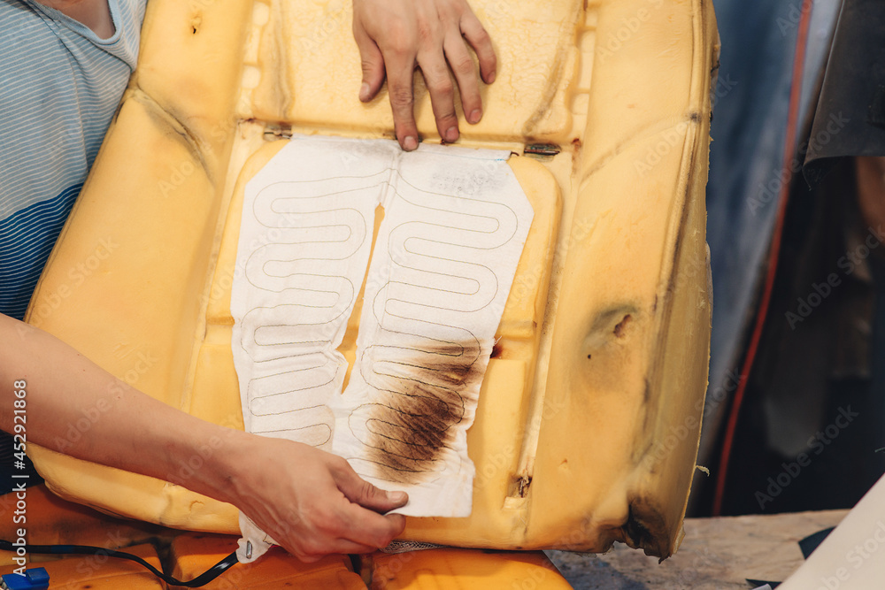 Obraz premium Repair of the old car seat. Car mechanic's hands is using tools.