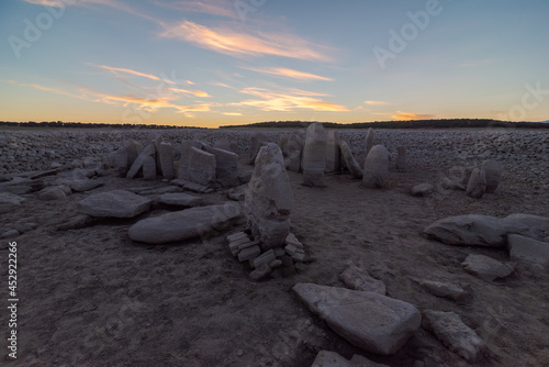 Spanish Stonehenge under cloudy sky with shiny sun in evening photo