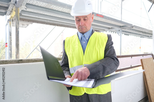 experienced elderly builder, construction team leader, construction engineer in white helmet protection signs documents at construction site for building renovation, civil engineering concept