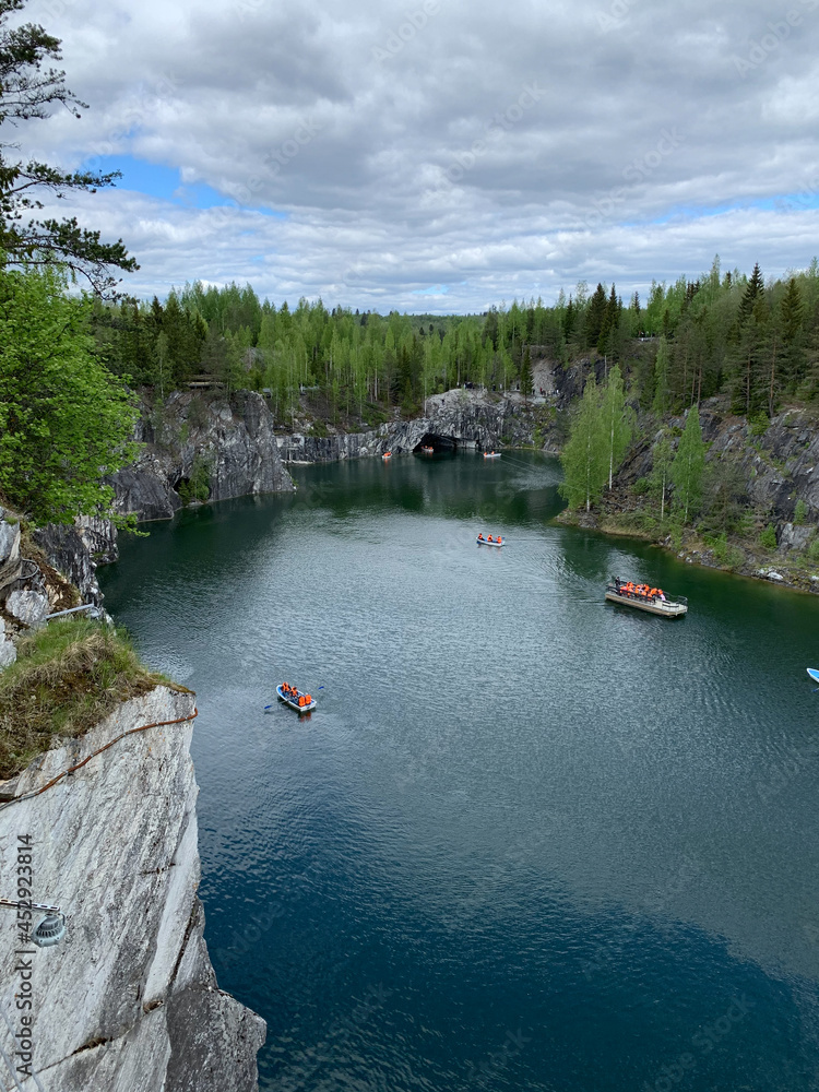 Top view of the cliffs, grotto and boats floating in the turquoise waters of Marble Canyon in Ruskeala Mountain Park on a summer day.