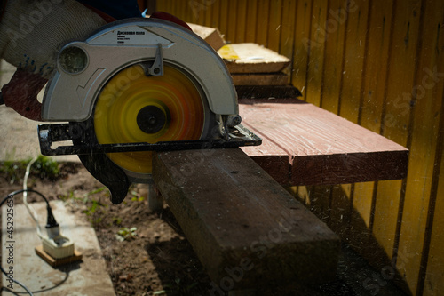 Builder saws a board with a circular saw in the cutting a wooden plank