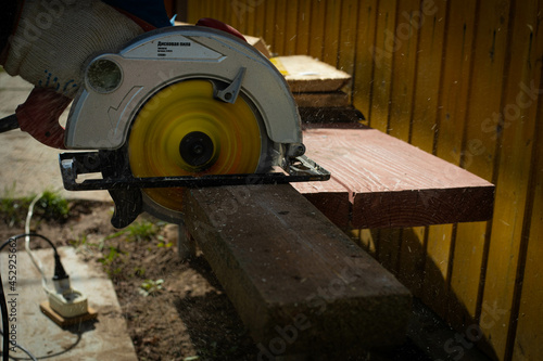 Builder saws a board with a circular saw in the cutting a wooden plank