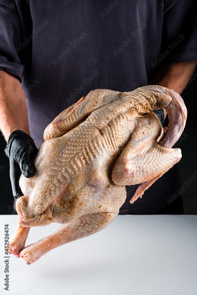 man's hands hold a large fresh turkey for a holiday dinner.
