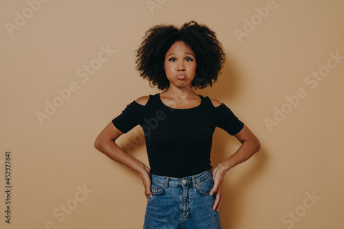 Fényképezés Funny carefree young dark skinned female puffing out her cheeks against nude stu