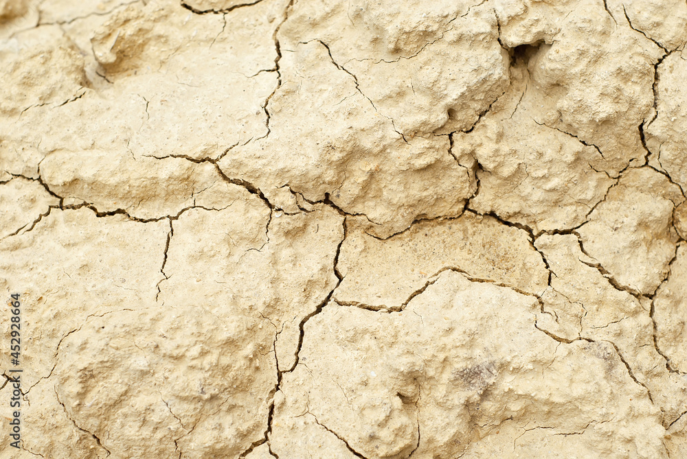 Fototapeta premium Dry yellow earth with cracks close up. The concept of global warming, cataclysms and drought.