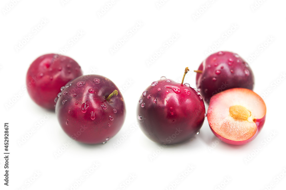 Ripe fresh organic plums whole and half in dew drops isolated on white background.	
