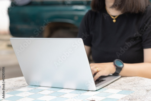 Woman using or typing laptop outside cafe restaurant with natural.