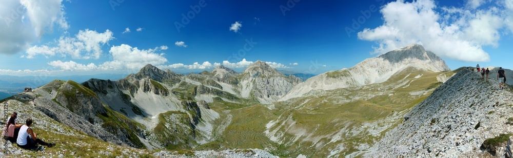 Hikers resting on the top of Mount Aquila with a great view of Gran Sasso mountain range, Abruzzo, Corno Grande, Corno Piccolo, Italy