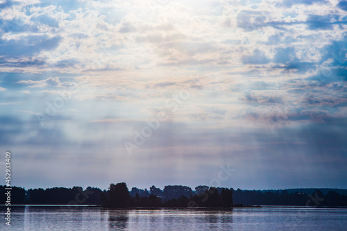 The rays of God in the river landscape. The sun's rays shine through the clouds over the water surface and the shore. Copy space © shaploff
