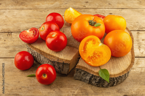 Assorted ripe tomatoes on a wooden stand. Fresh red and orange organic vegetables