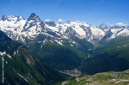 Sharp peaks of the Dombay Mountains, covered with snow, with a village at the foot of the mountains
