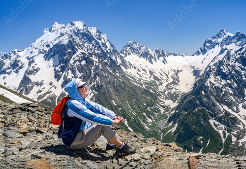 A tourist high in the Dombay Mountains, covered with snow, admires the expanse photo