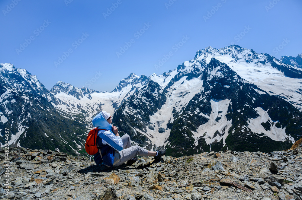 A tourist high in the Dombay Mountains, covered with snow, admires the expanse A tourist high in the Dombay Mountains, covered with snow, admires the expanse