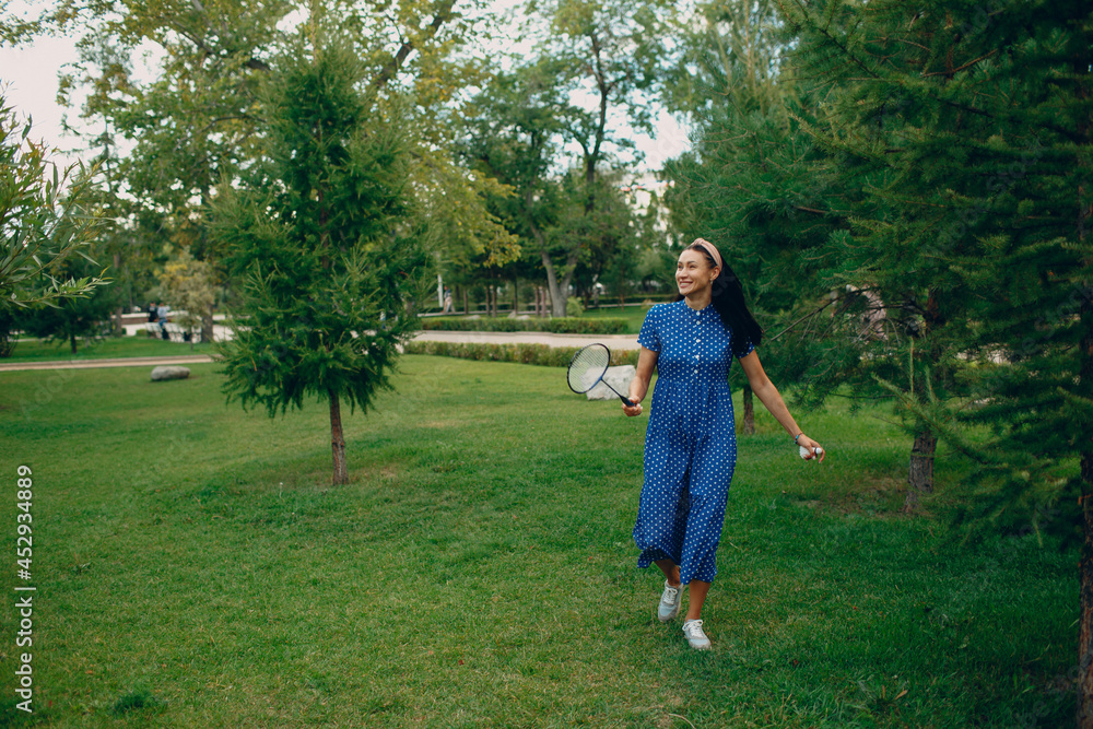 Young adult woman playing badminton in the park.