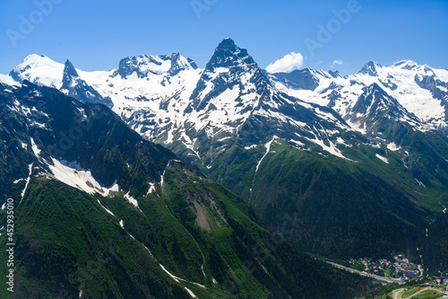 Sharp peaks of the Dombay Mountains, covered with snow, with a village at the foot of the mountains