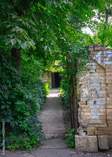 Entrance to the courtyard of an old house with a dilapidated brick fence