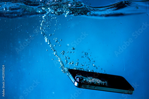 black and white phone dropped into the water. phone in water.phone in water bubbles.phone sinks in water