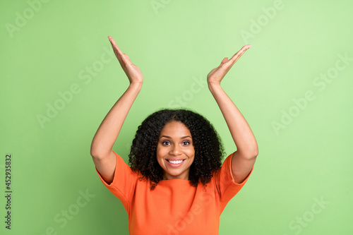 Photo of young black woman happy positive smile gesture hands advertise isolated over green color background © deagreez