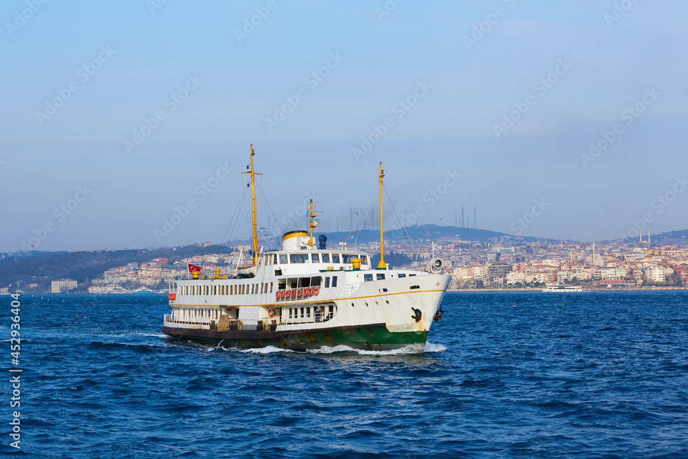 Tourist boat sails on the Golden Horn in Istanbul at sunset, Turkey.