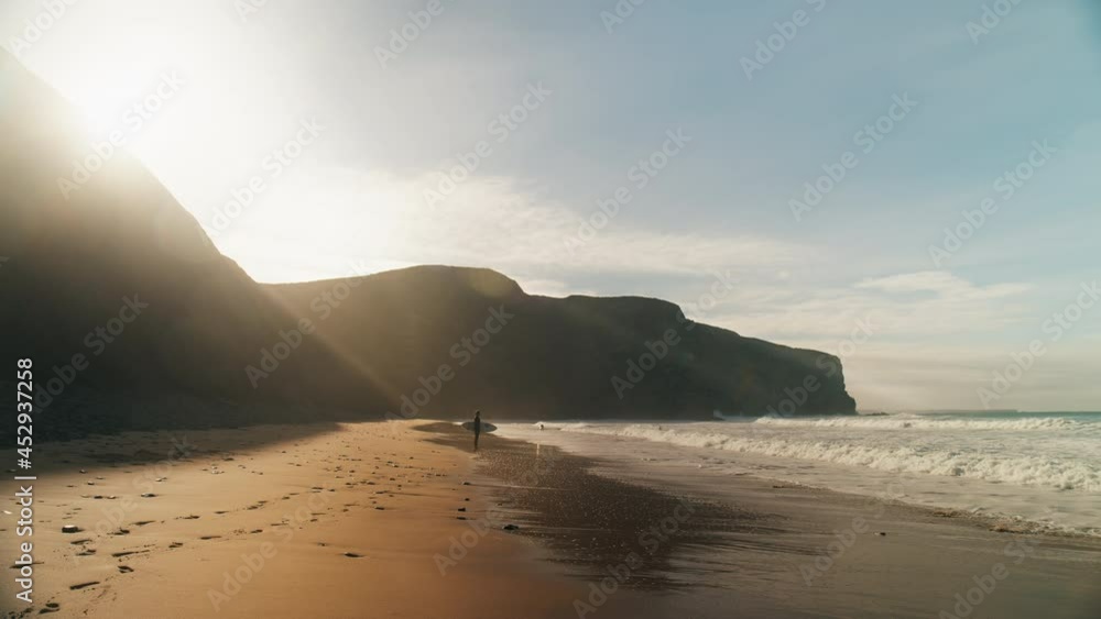 Surfer prepares to go into cold ocean water, stretch and attach leash to ankle. Safety and preparation for extreme sport. Big wave surfing in portugal. Cinematic and inspiring surfing lifestyle image Surfer prepares to go into cold ocean water, stretch and attach leash to ankle. Safety and preparation for extreme sport. Big wave surfing in portugal. Cinematic and inspiring surfing lifestyle image