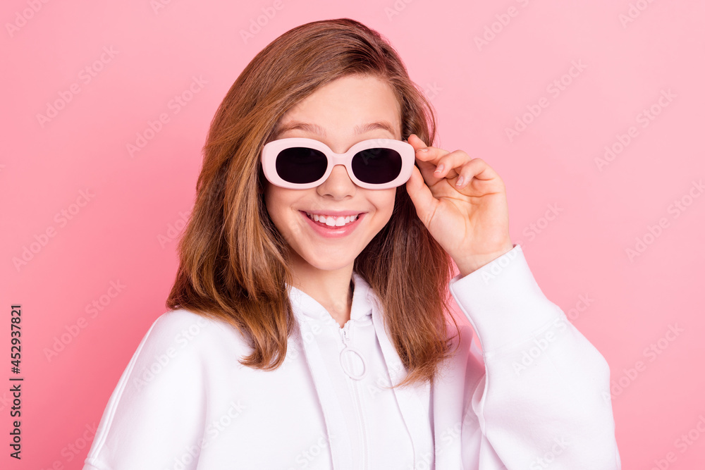 Photo portrait little girl in white hoodie smiling wearing sunglass isolated pastel pink color background Photo portrait little girl in white hoodie smiling wearing sunglass isolated pastel pink color background