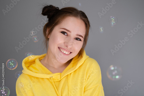 woman in yellow among soap bubbles on grey background