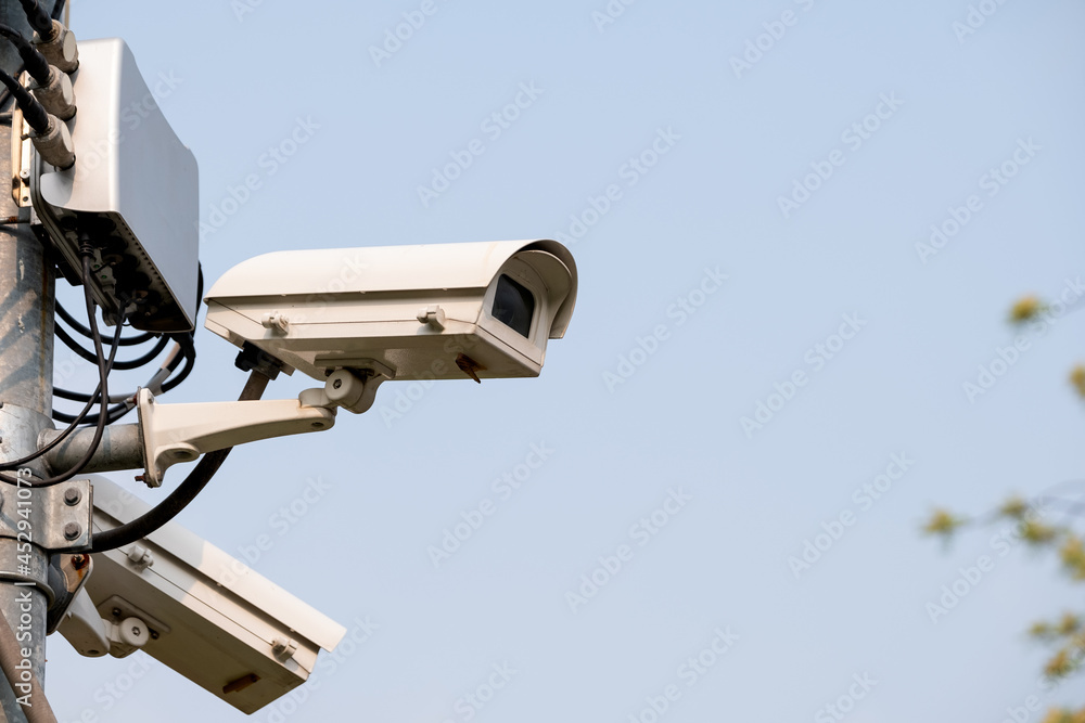 Closed-circuit camera attach on top of pole in park or public area for security reason with clear sky as background. Closed-circuit camera attach on top of pole in park or public area for security reason with clear sky as background.