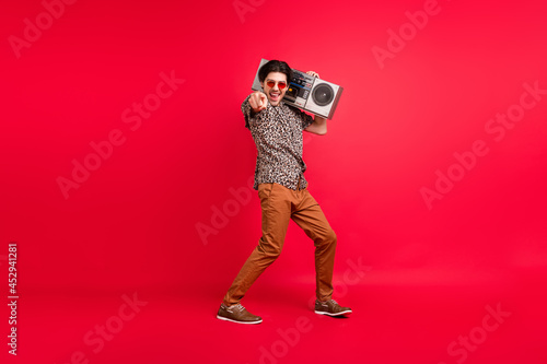 Full size photo of funky funny excited smiling male dancing point finger choose you isolated on red color background © deagreez