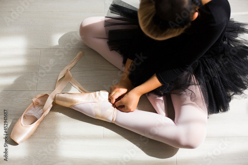 Legs and black fluffy skirt of little balerina wearing pail pink pointe shoes with ribbons photo