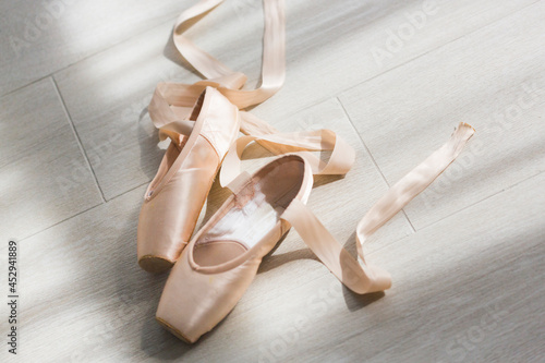 A pair of balerina's pail pink pointe shoes or ballet shoes with ribbons