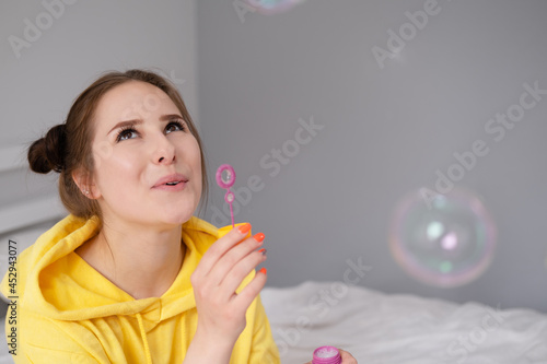 woman in yellow among soap bubbles on grey background