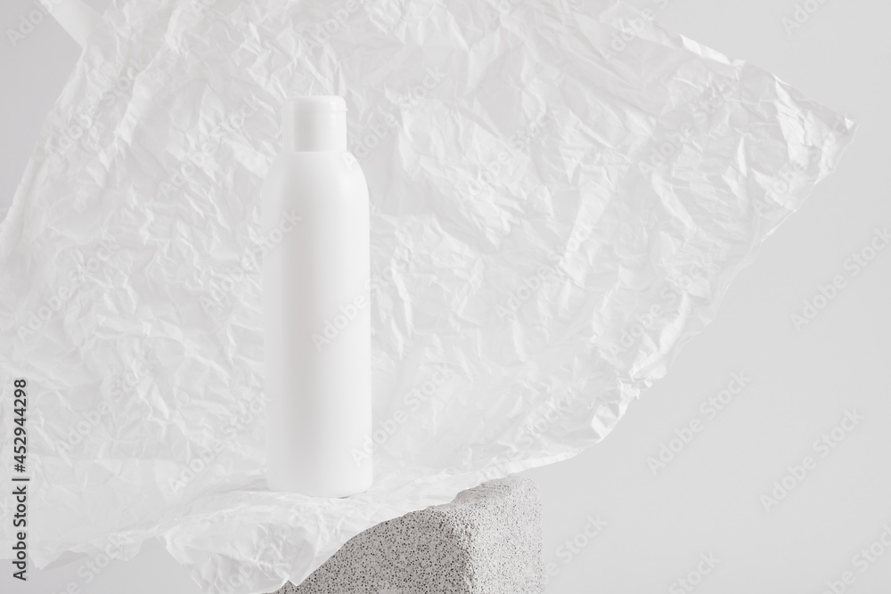white bottle on a gray concrete podium against a background of white crumpled paper, cosmetics mock up white bottle on a gray concrete podium against a background of white crumpled paper, cosmetics mock up