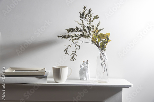 A vase with dry eucalyptus, pieces of paper, a figurine with a fox, and a cup of coffee. Scandinavian style.