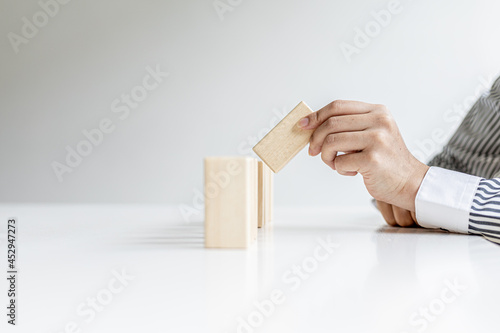 A woman is holding wooden blocks in a row, she grabs the center piece to complete them, the wooden block arrangement conveys the business operation by efficient management. Business idea.