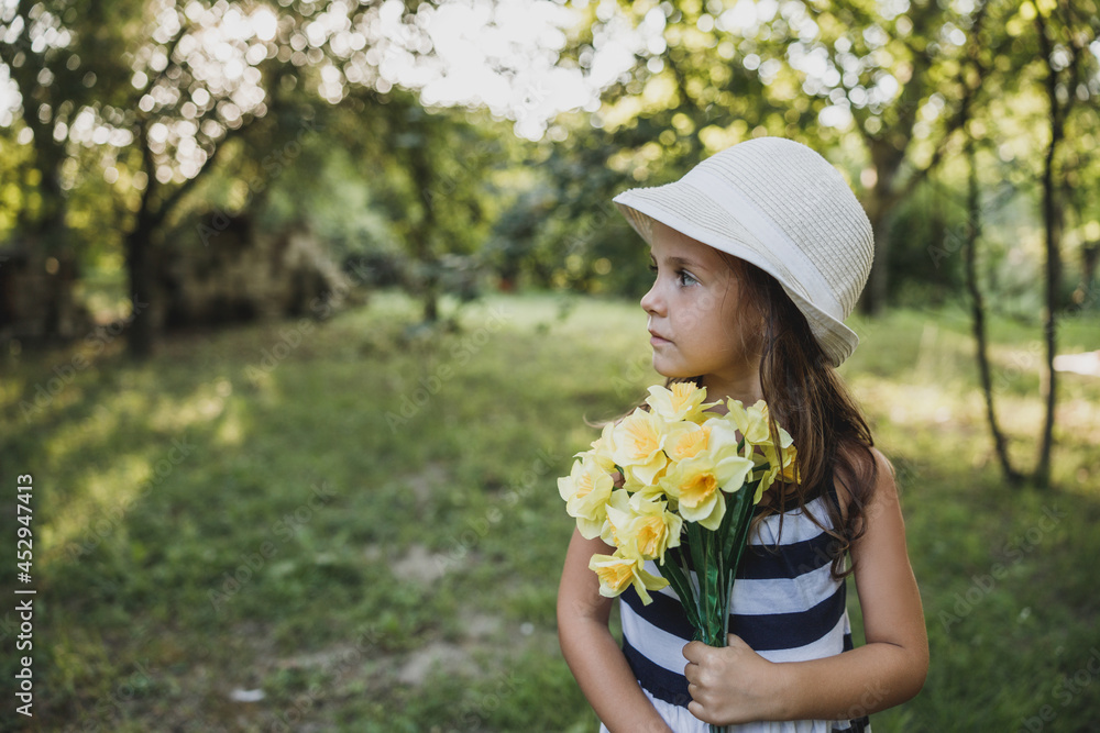 Little Girl With Bouquet Of Daffodils In Nature