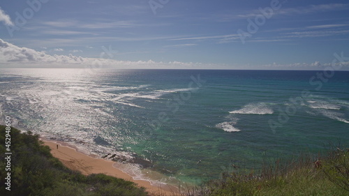 View from above to Diamond Head Beach Park. People swim in the ocean. Yellow sand on the beach on the tropical island of Oahu Hawaii. The turquoise color of the Pacific Ocean water.