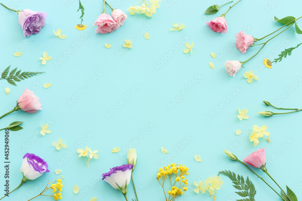 Top view image of pink, yellow and purple flowers composition over pastel blue background .Flat lay