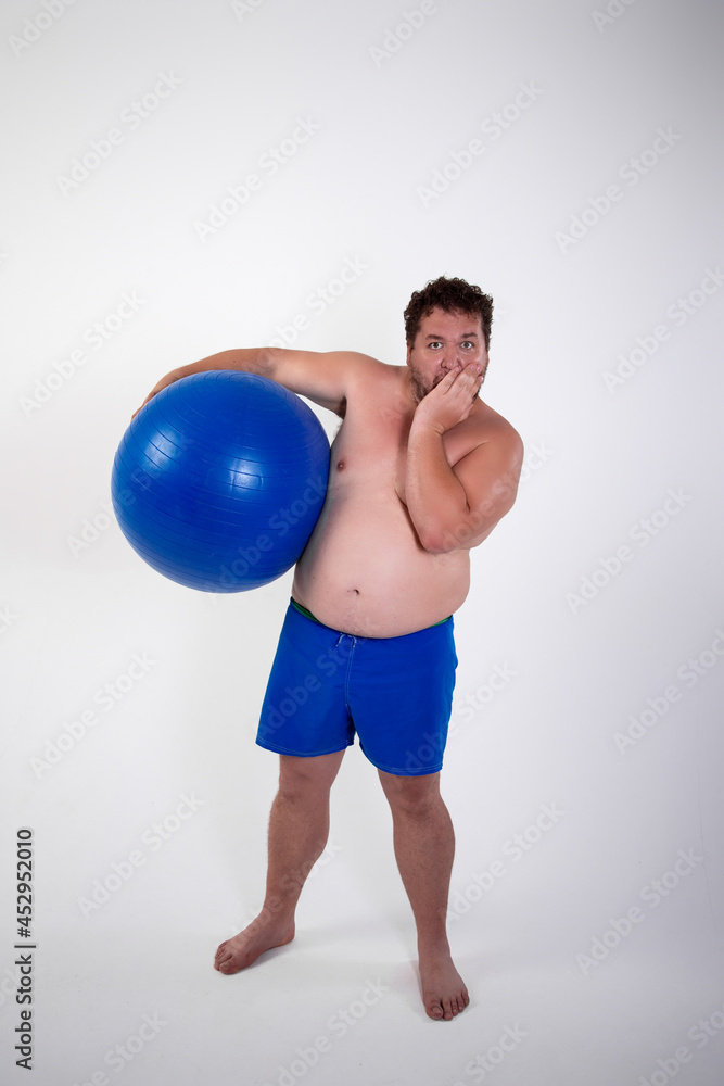 Funny fat man training with a fitness ball. Adult guy on a white background. Copy space. Active sports with a diet. Funny fat man training with a fitness ball. Adult guy on a white background. Copy space. Active sports with a diet.