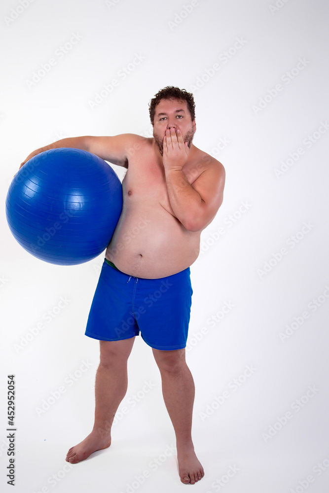 Funny fat man training with a fitness ball. Adult guy on a white background. Copy space. Active sports with a diet.